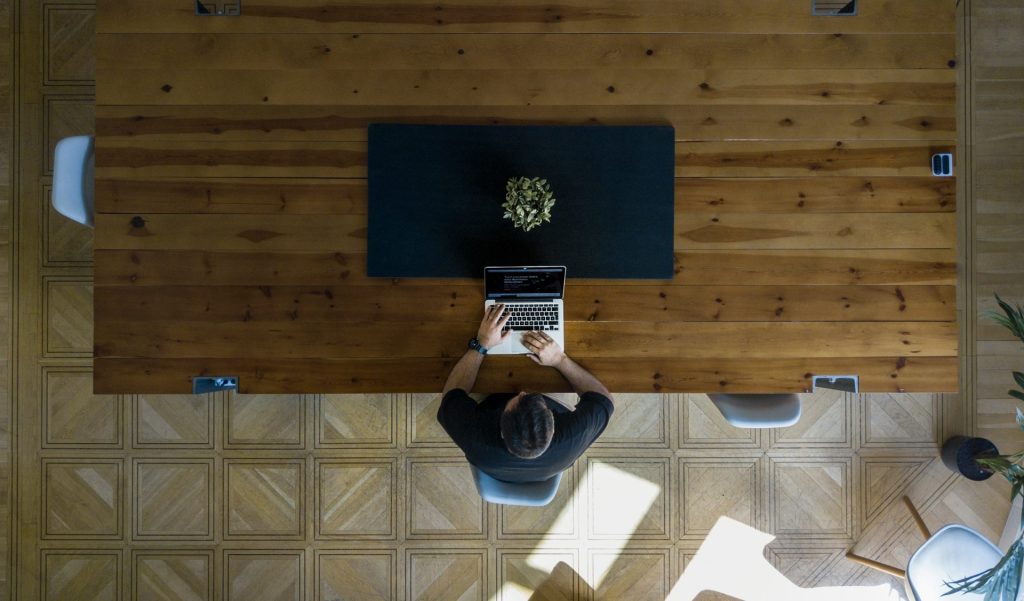 man wearing black shirt sitting on chair using laptop